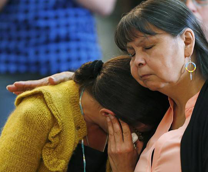 A woman is comforted at a '60s Scoop gathering before a provincial apology by Premier Greg Selinger June. Manitoba's First Nations children's advocate says the province continues to seize children instead of support their families.