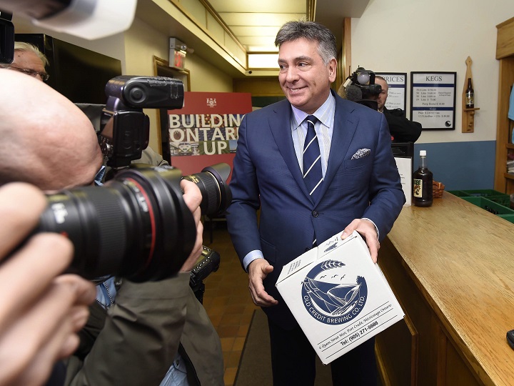 Ontario Finance Minister Charles Sousa buys a case of beer at the Old Credit Brewing Co. Ltd. at a pre-budget day photo-op in Port Credit, Ont., on Wednesday, April 22, 2015. 