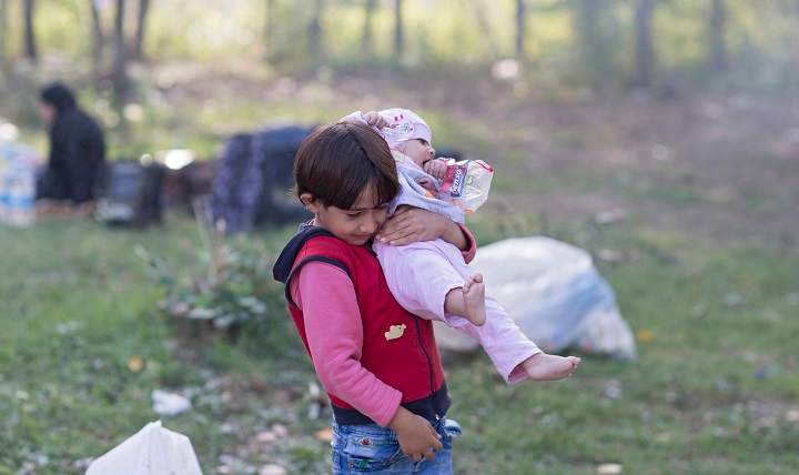 A Syrian refugee girl carries her sister as refugees rest at Sarayici Park, as they wait for permission to pass the Turkish-Greek border in Edirne, Turkey, 20 September 2015. 