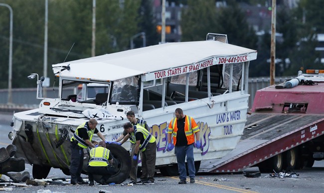 Seattle Police officers photograph the front tire and wheel of a "Ride the Ducks" tourist vehicle before the bus is loaded onto a flatbed tow truck Thursday, Sept. 24, 2015, after it was involved in a fatal crash with a charter passenger bus earlier in the day in Seattle.