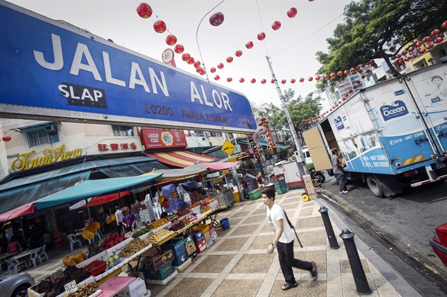 A tourist walks past Malaysia's famous eatery street, Jalan Alor, a popular tourist spot in Kuala Lumpur, Malaysia on Friday, Sept. 25, 2015. The U.S. Embassy issued an advisory Thursday saying it has credible threat information and urged its citizens to avoid Alor Street, located in a shopping belt in the city center, and its immediate surrounding areas. (AP Photo/Joshua Paul).