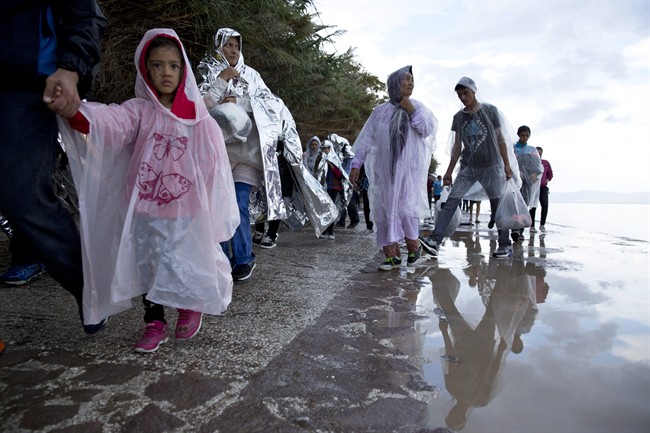 Afghan migrants walk on a street in the rain, after they arrived with from Turkey to the shores of the Greek island of Lesbos, Thursday, Sept. 24, 2015. More than 260,000 asylum-seekers have arrived in Greece so far this year, most reaching the country's eastern islands on flimsy rafts or boats from the nearby Turkish coast.(AP Photo/Petros Giannakouris).