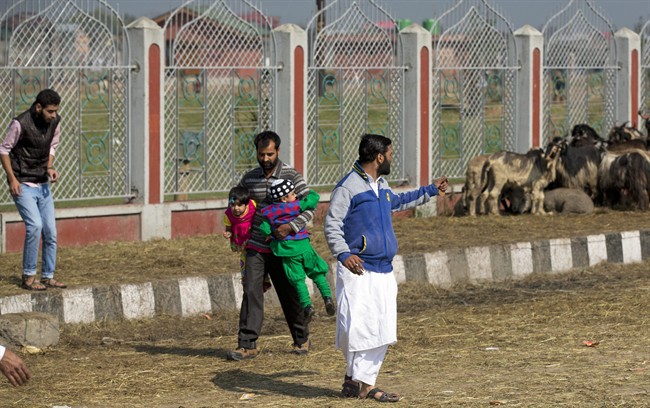 A Kashmiri man carries children and runs for cover after offering special Eid prayers, as protestors gather outside Eidgha, a prayer ground, in Srinagar, Indian controlled Kashmir, Friday, Sept. 25, 2015. Police fired teargas and rubber bullets to disperse hundreds of Kashmiris protesting a court ruling upholding a colonial-era law banning cow slaughter and the sale of beef in the Indian-controlled portion of Kashmir. (AP Photo/Dar Yasin).