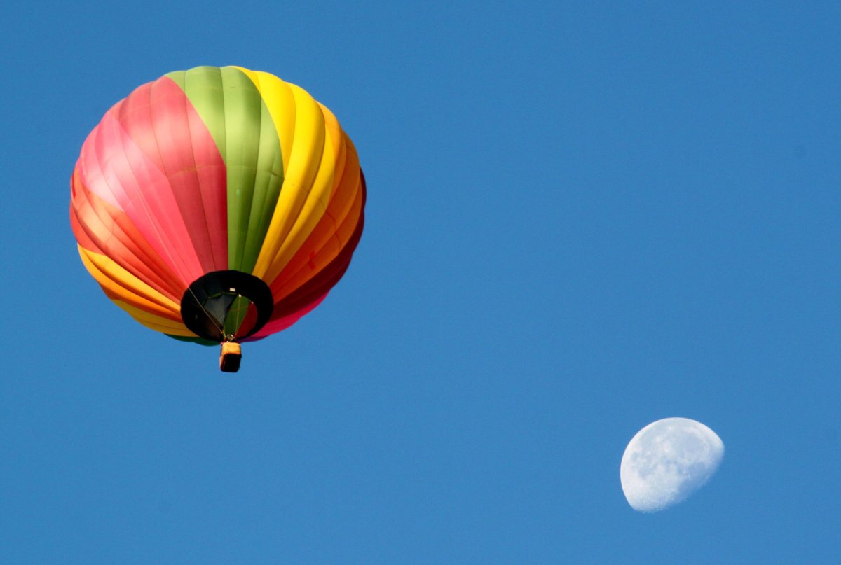 A hot air balloon passes in front of the moon as dozens of balloons lifted off in advance of the annual Albuquerque International Balloon Fiesta.