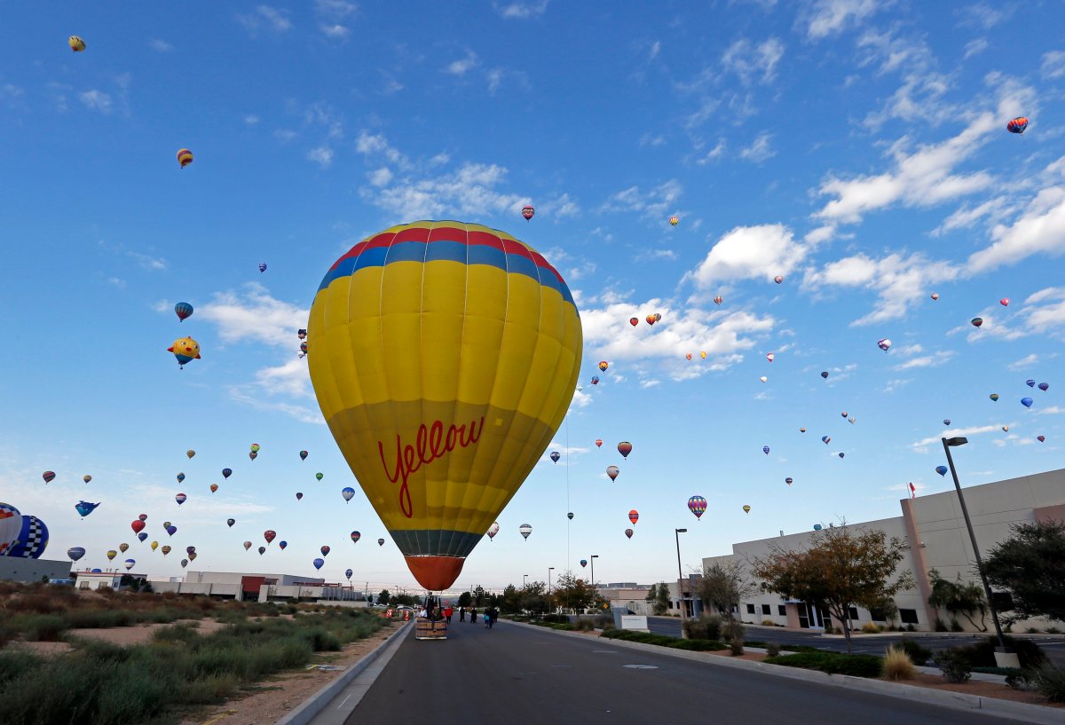 A hot hair ballon lands on a service road as many others fly during the opening day of the 44th International Balloon Fiesta in Albuquerque, N.M., Saturday, Oct. 3, 2015.