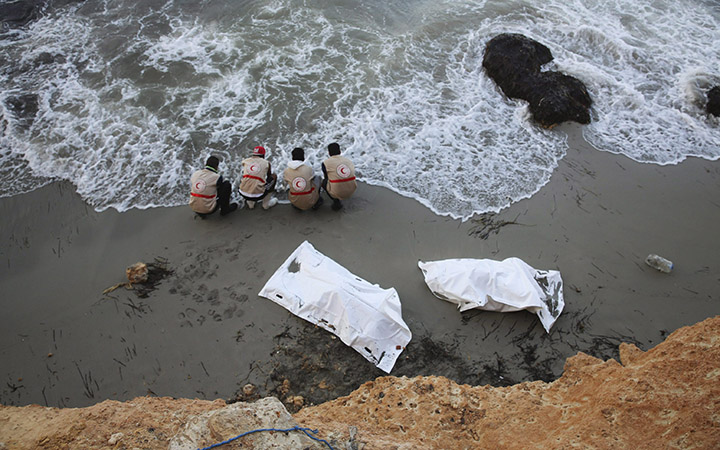 Members of the Libyan Red Crescent wash their hands at the shore after they placed bodies of migrants found on the eastern shore of Tripoli, Libya into bags.