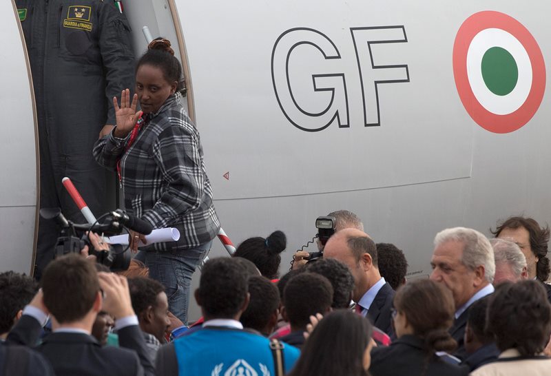 An Eritrean refugee waves as she boards an Italian Financial police aircraft which will take her and other 18 refugees to Sweden, at Rome's Ciampino airport, Friday, Oct. 9, 2015. 