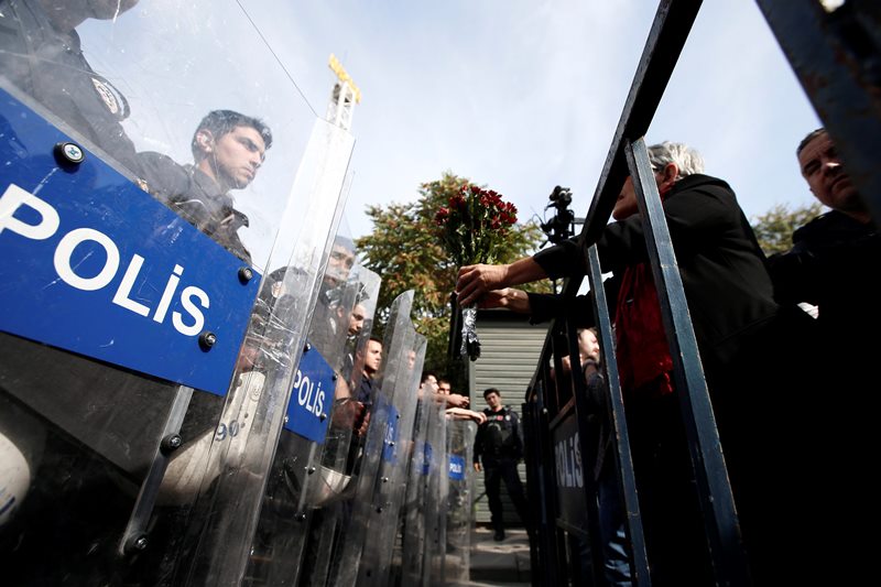 A protester offers carnations to Turkish police blocking the way to the site of Saturday’s explosions in Ankara, Turkey, Sunday, Oct. 11, 2015.