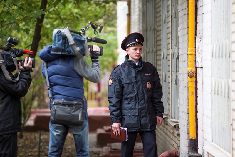 Members of the media film as a Russian policeman stands at an entrance of the building where homemade explosives were found in an apartment, in Moscow, Russia, Monday, Oct. 12, 2015.