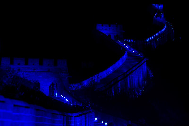 Chinese men stand near the entrance to a tower along a section of the Great Wall of China lit by blue light to commemorate the 70th anniversary of the United Nations on the outskirts of Beijing, China, Saturday, Oct. 24, 2015. 