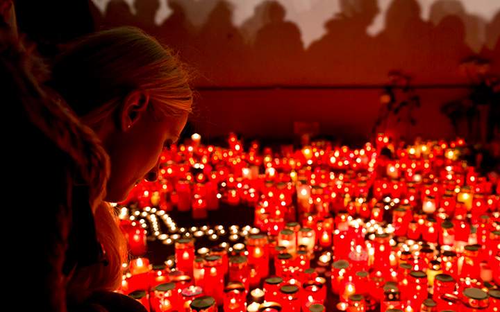 A girl lights candles outside the compound that housed the nightclub where a fire occurred in the early morning hours in Bucharest, Romania, Saturday, Oct. 31, 2015.