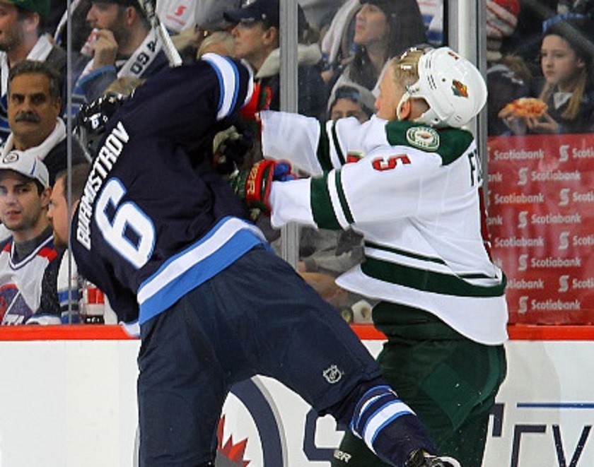 Christian Folin #5 of the Minnesota Wild sends Alexander Burmistrov #6 of the Winnipeg Jets flying after a first period check along the boards at the MTS Centre on October 25, 2015 in Winnipeg, Manitoba.
