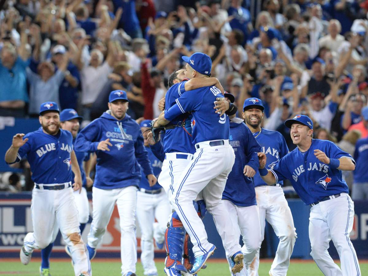 Toronto Blue Jays' Roberto Osuna, center right, and catcher Dioner Navarro embrace as the Blue Jays celebrate on the field .