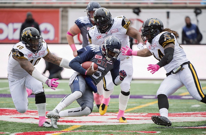 Montreal Alouettes quarterback Kevin Glenn, centre, is surrounded by Hamilton Tiger-Cats' Eric Norwood (40), Bryan Hall (6) and Taylor Reed, right, during first half CFl football action in Montreal, Sunday, October 18, 2015. 