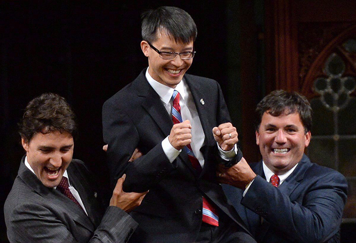 Liberal Leader Justin Trudeau and MP Dominic LeBlanc, right, escort new Liberal MP Arnold Chan in the House of Commons on Parliament Hill in Ottawa on Sept. 15, 2014. The federal government remains locked in a battle with telecom companies over $2.4 million in late fees because department phone bills weren't paid on time.