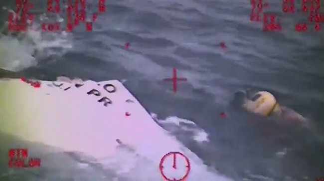 In this Sunday, Oct. 4, 2015 photo made from video and released by the U.S. Coast Guard, a Coast Guard crew member investigates a life boat, that was found from the missing ship El Faro. On Monday, four days after the ship vanished, the Coast Guard concluded it sank near the Bahamas in about 15,000 feet of water. One unidentified body in a survival suit was spotted, and the search went on for any trace of the other crew members. The search continued Tuesday, Oct. 6, 2015. 