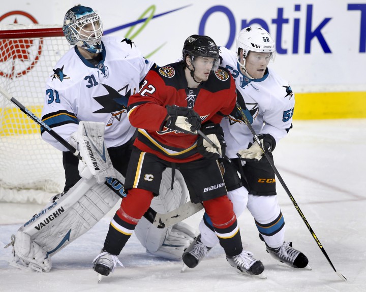 Calgary Flames' Paul Byron, center, playing against San Jose Sharks' Matt Irwin, right, and goalie Antti Niemi during a game in Calgary, Alberta on Dec. 6, 2014.