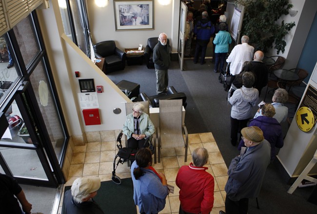 Voters form a line as they wait to cast their ballots in Sidney, B.C., Monday, Oct. 19, 2015.