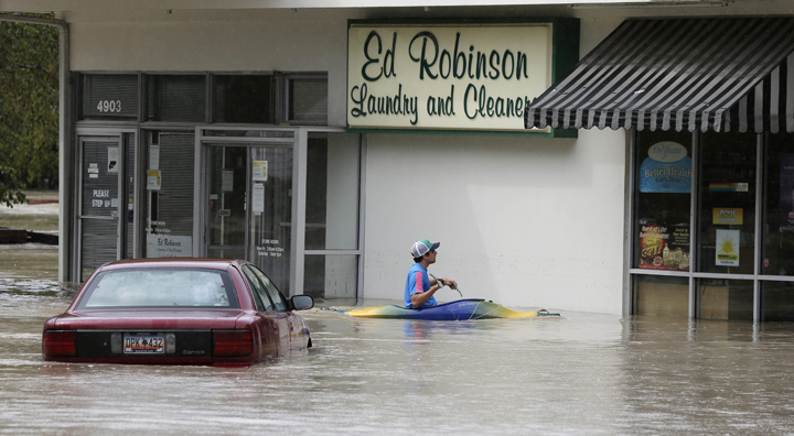 Jordan Bennett, of Rock Hill, S.C., paddles up to a flooded store in Columbia, S.C., Sunday, Oct. 4, 2015.