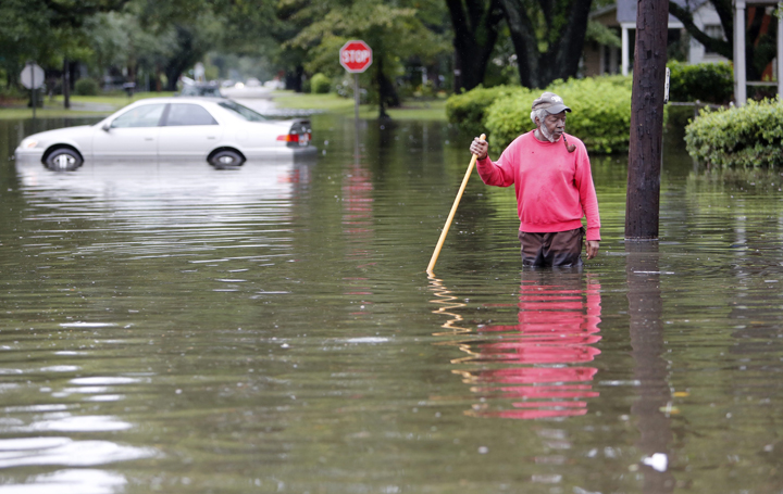David Linnen takes a yard rake to clear drains in front of Winyah Apartments in Georgetown, S.C., Sunday, Oct. 4, 2015.