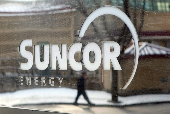 A pedestrian is reflected in a Suncor Energy sign in Calgary, Feb. 1, 2010. 