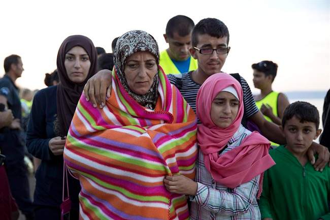 A Syrian family walks after they arrived with other refugees from Turkey to the shores of the Greek island of Lesbos, on a inflatable dinghy, Friday, Sept. 25, 2015. 