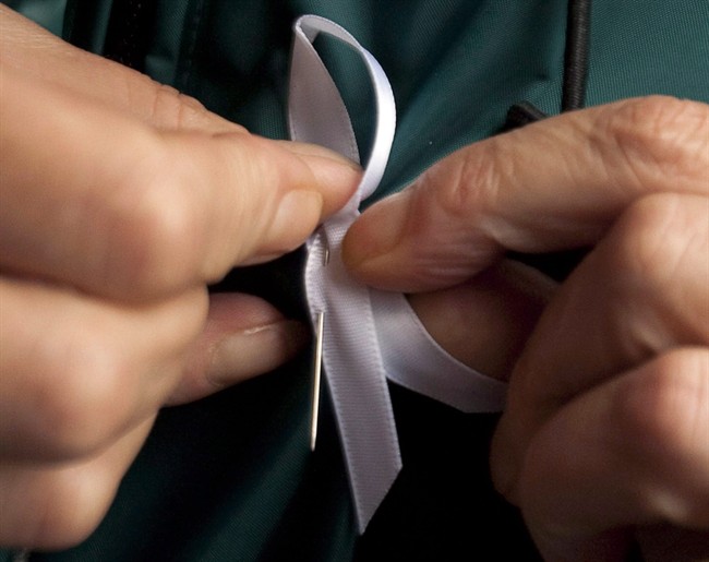 A woman puts on a white ribbon during an anti-violence against women event. 