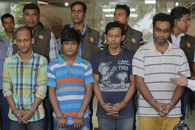 Bangladesh police personnel, standing behind, present before media four suspects they arrested in the killing of an Italian aid worker last month, in Dhaka, Bangladesh, Monday, Oct. 26, 2015. Italian aid worker Cesare Tavella was gunned down by motorcycle-riding assailants on Sept. 28 while jogging in the diplomatic quarter of Dhaka, Bangladesh's capital. Police said Monday that the alleged gunmen had confessed to being hired to attack "a white man" in order to destabilize the impoverished South Asian nation. (AP Photo/ A.M. Ahad).
