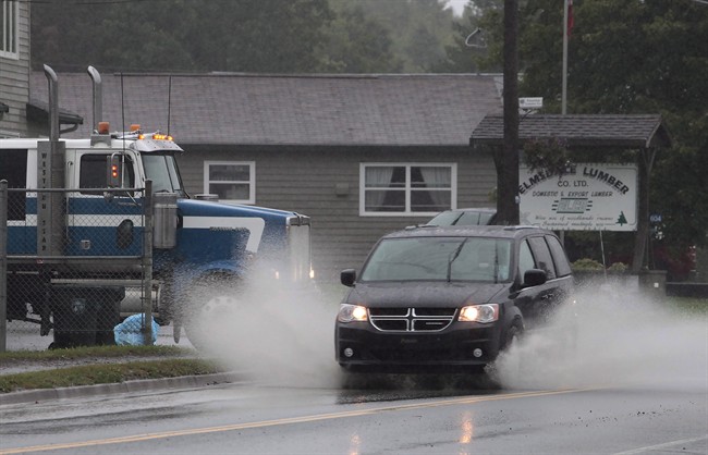A mini-van splashes through a rain puddle during the morning commute in Elmsdale, N.S., on Thursday, October 1, 2015.