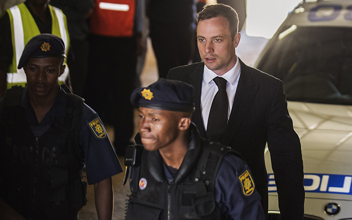 South African Paralympian athlete Oscar Pistorius is escorted to a police vehicle to be transported to prison following his sentencing at the High Court in Pretoria, on October 21, 2014. 