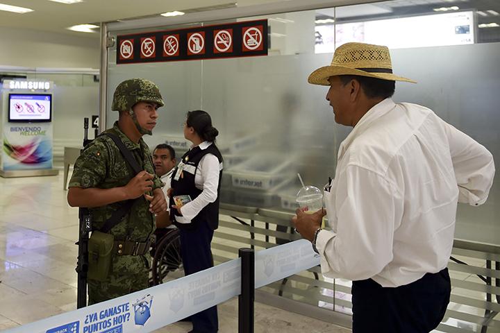 A Mexican soldier speaks with a man at the International airport in Mexico City on July 16, 2015.