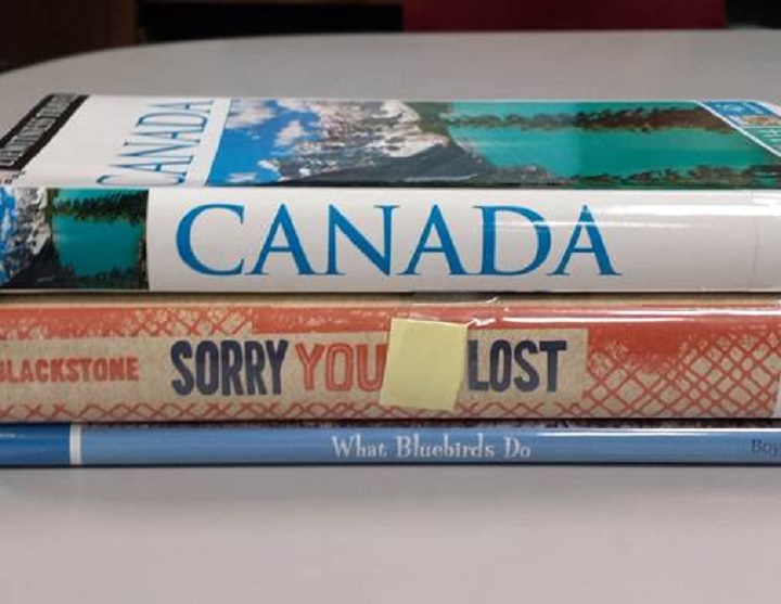 A picture posted on the Kansas City Public Library's Twitter page shows three books stacked on top of each other with the spine reading, "Canada. Sorry you lost. What Bluebirds Do.".