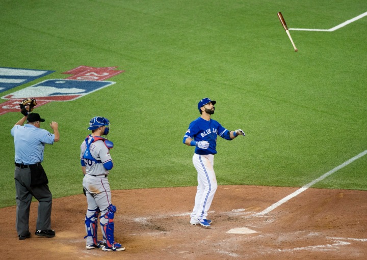 Toronto Blue Jays' Jose Bautista, right, flips his bat in the air while celebrating a three-run home run in front of Texas Rangers catcher Chris Gimenez during seventh inning game five American League Division Series baseball action in Toronto on Wednesday, October 14, 2015.
