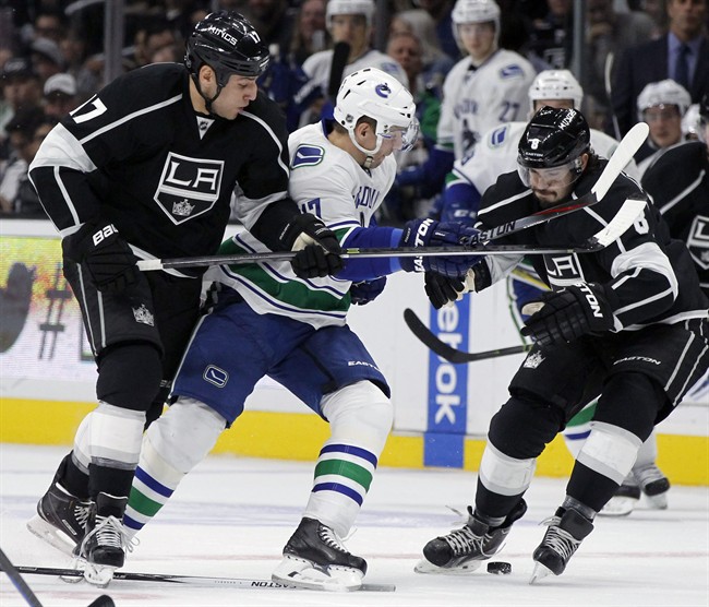 Los Angeles Kings left wing Milan Lucic (17) and defenceman Drew Doughty (8) battle Vancouver Canucks right wing Radim Vrbata (17), of the Czech Republic, for the puck during the first period of an NHL hockey game in Los Angeles, Tuesday, Oct. 13, 2015.