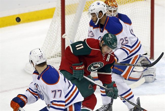 A shot goes high and wide past Minnesota Wild’s Zach Parise (11) as Edmonton Oilers' Darnell Nurse (25) defends in the first period of an NHL hockey game, Tuesday, Oct. 27, 2015, in St. Paul, Minn.