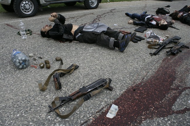 In this Thursday, May 9, 2013, file photo bodies of killed militants lie surrounded by different kinds of explosives and weapons at Gubden in Dagestan, Russia. 