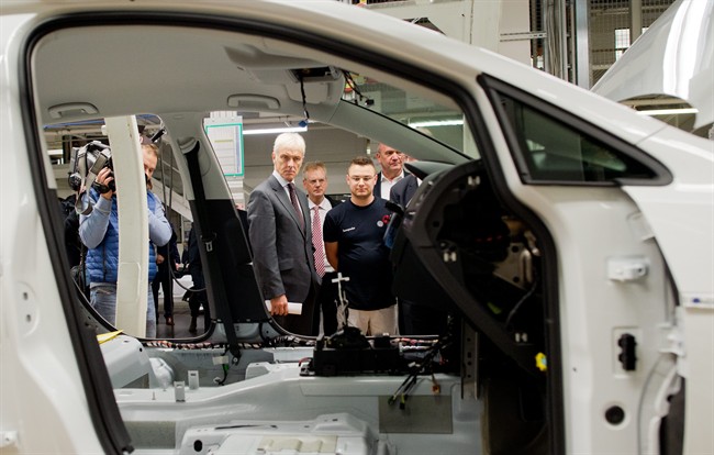 Volkswagen CEO Matthias Mueller, centre, looks at the assembly line during a tour of the VW plant in Wolfsburg, Germany Wednesday Oct. 21, 2015.