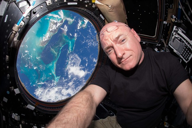 Scott Kelly poses for a selfie photo in the "Cupola" of the International Space Station with the Bahamas seen below.