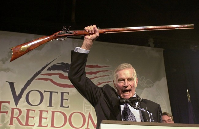 In this Monday, Oct. 21, 2002 file photo, National Rifle Association President Charlton Heston holds up a rifle as he addresses gun owners during a "get-out-the-vote" rally in Manchester, N.H.