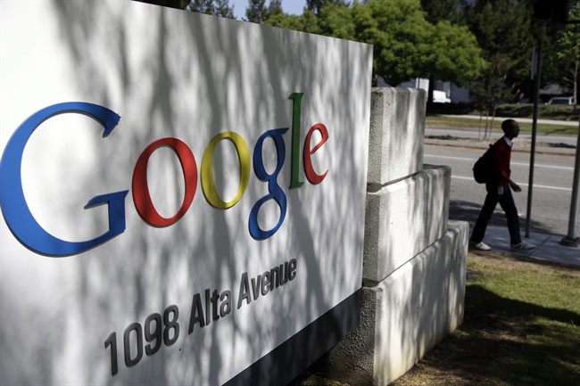 FILE - In this June 5, 2014 photo, a man walks past a Google sign at the company's headquarters in Mountain View, Calif. Google is escalating an attack on Microsoft's lucrative Office software in an attempt to hit its longtime rival where it will hurt the most.