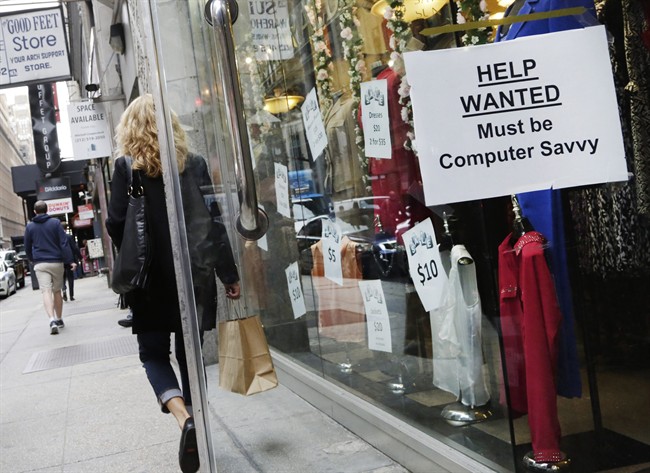 A a shopper walks past a store with a "Help Wanted" sign in the window.