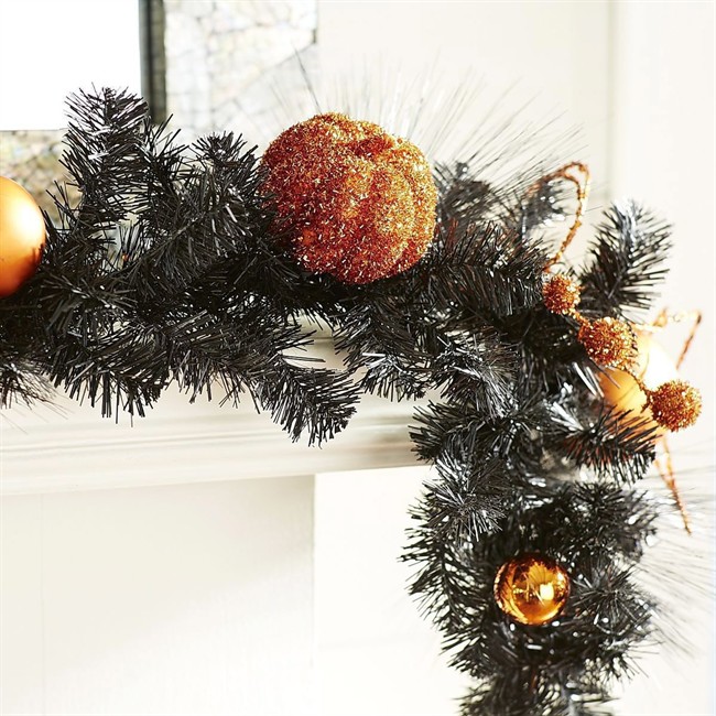 This black pine garland from Pier 1 is embellished with orange pumpkins and ornaments, making it a great Halloween mantel or table decoration.