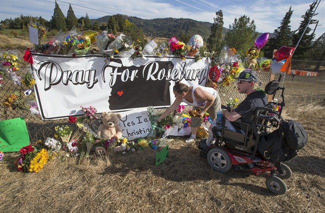Candida Miller, left, and Brandon Snyder leave flowers at a site of a growing memorial to victims of the mass shooting at Umpqua Community College in Roseburg, Ore., Tuesday, Oct. 6, 2015. 