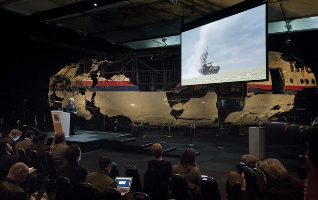 A video show the launch of a BUK missile, while a part of the reconstructed forward section of the fuselage is displayed behind, as Tjibbe Joustra, left, head of the Dutch Safety Board presents the board’s final report into what caused Malaysia Airlines Flight 17 to break up high over Eastern Ukraine last year, killing all 298 people on board, during a press conference in Gilze-Rijen, central Netherlands, Tuesday, Oct. 13, 2015.