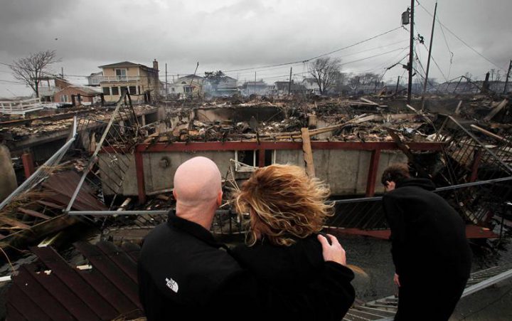 In this Oct. 30, 2012 file photo, a couple surveys the destruction left behind by Superstorm Sandy in the Breezy Point section of New York.