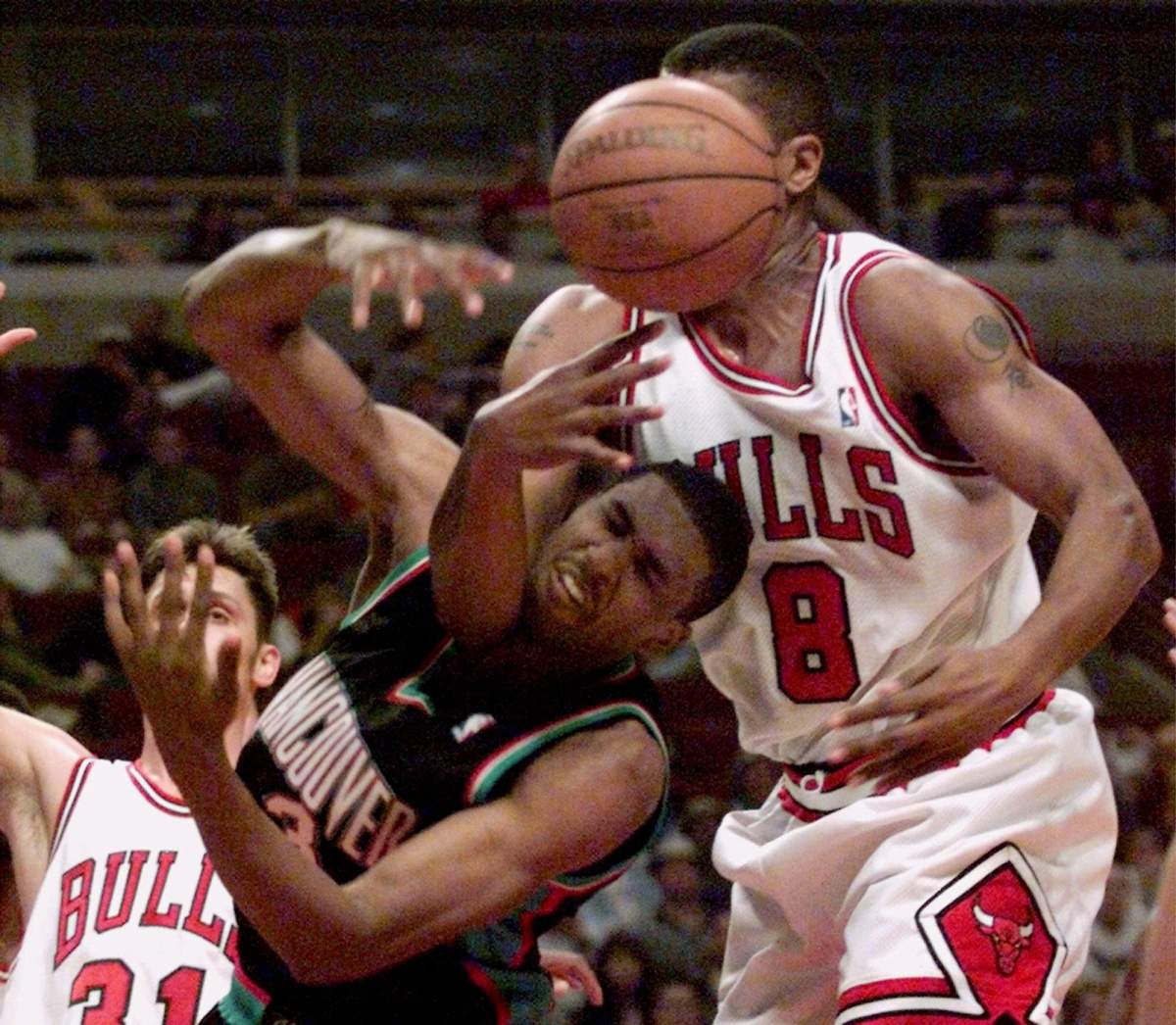 Vancouver Grizzlies’ Shareef Abdur-Rahim (3) is fouled while getting the ball knocked away by the Chicago Bulls’ Dickey Simpkins (8) in the first quarter Sunday, April 4, 1999, in Chicago. Looking on is the Bulls’ Brent Barry (31). (AP Photo/Frank Polich)