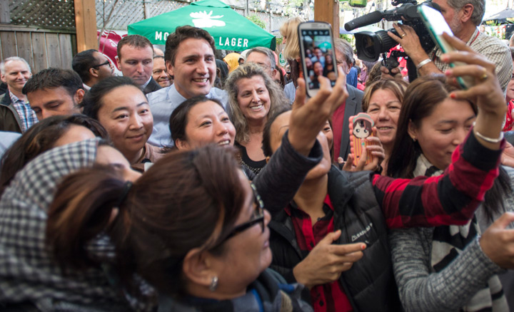 A group of women gathers around Liberal Leader Justin Trudeau for a photograph during a campaign stop at a bar Tuesday, October 13, 2015 in Toronto.