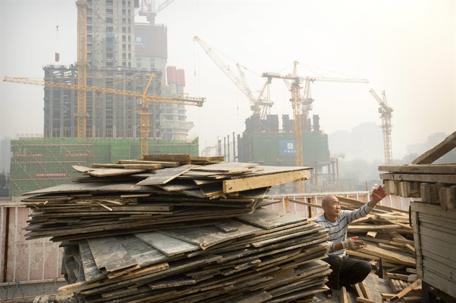 A worker tosses boards onto the back of a truck at a construction site in Beijing. 