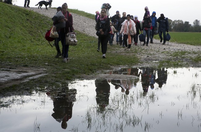 A group of migrants walk past a puddle after crossing from Croatia, in Brezice, Slovenia Monday, Oct. 19, 2015. 