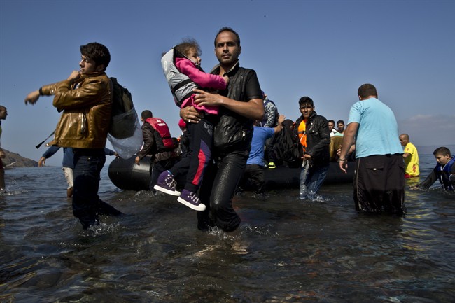 A Syrian refugee man carrying his daughter rushes to the beach as he arrives on a dinghy from the Turkish coast to the northeastern Greek island of Lesbos, Sunday, Oct. 4 , 2015. 